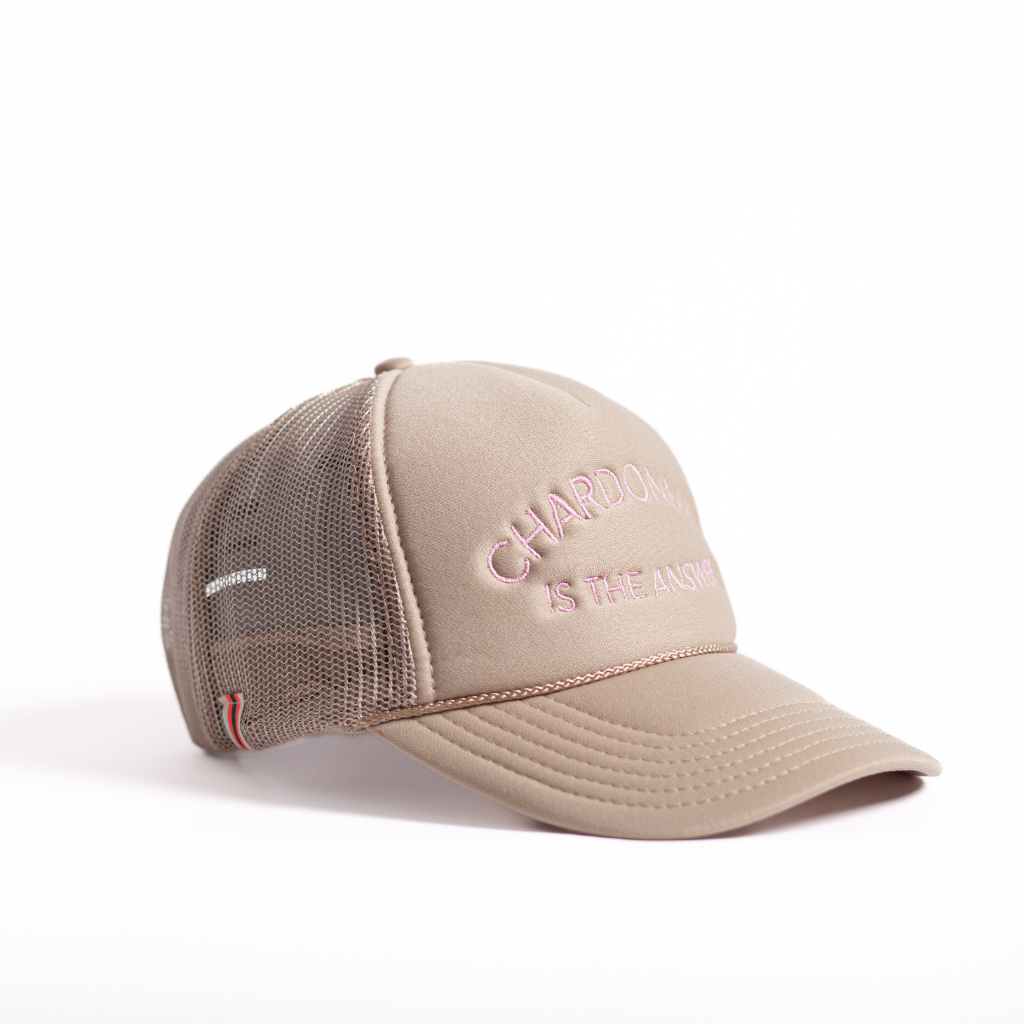 Tan mid profile trucker hat with light pink embroidered chardonnay is the answer