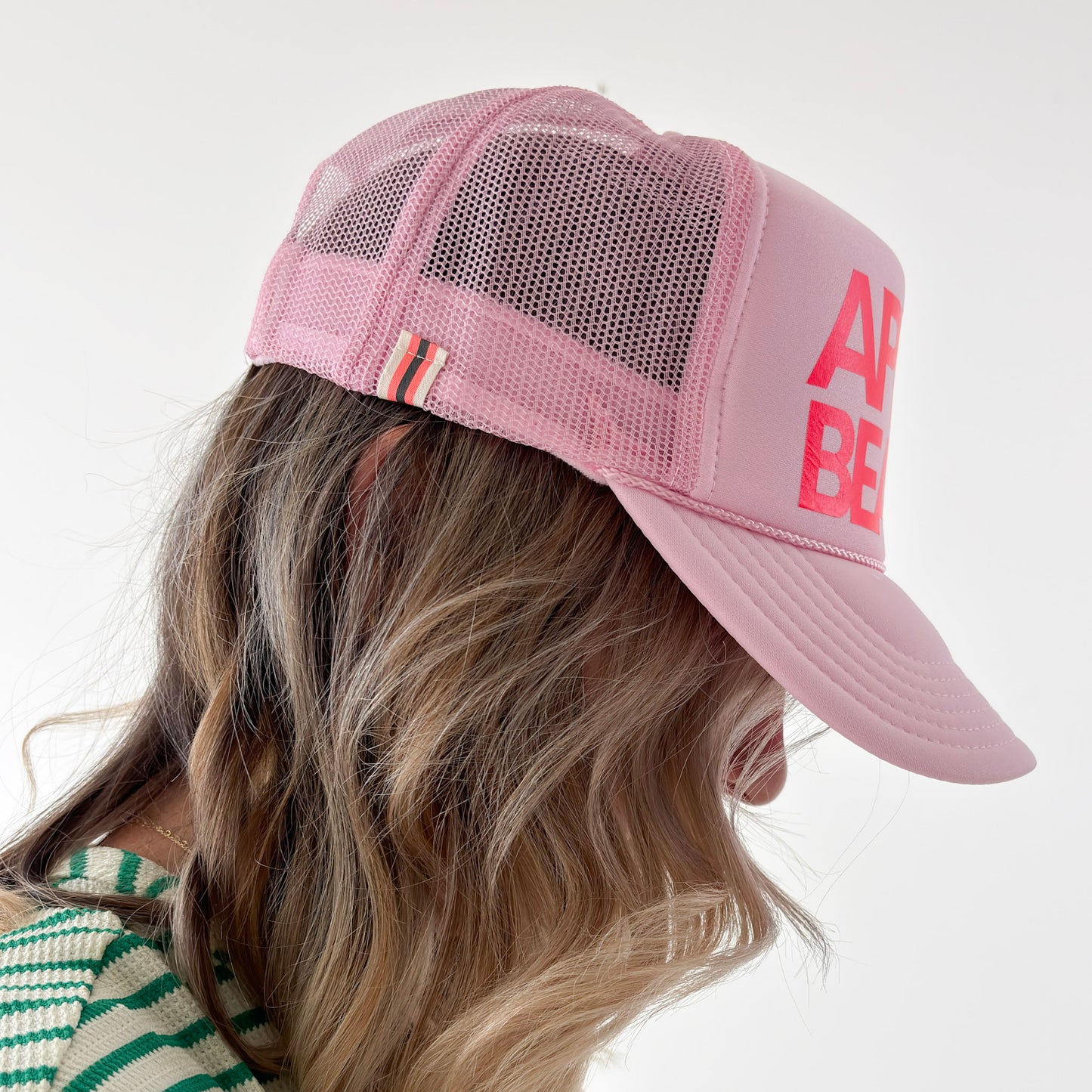 Women's light pink high profile trucker hat with neon coral après beach print