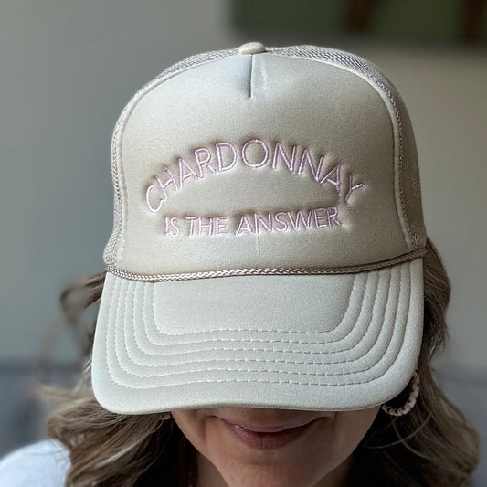Tan mid profile trucker hat with light pink embroidered chardonnay is the answer