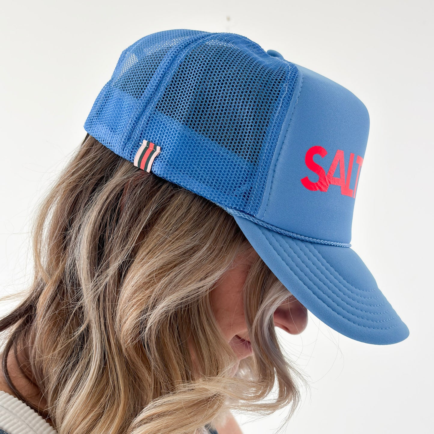 Women's bright blue high profile snap back foam trucker hat with neon coral "salty af." graphic