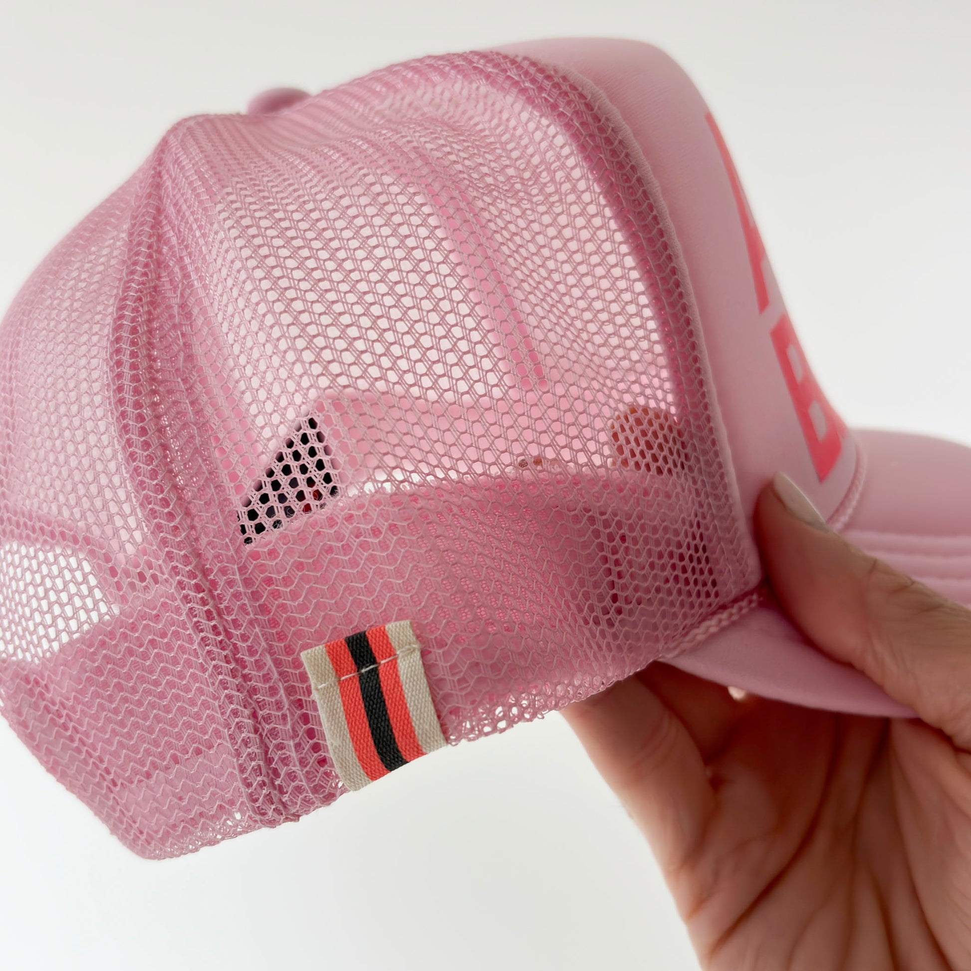 Women's light pink high profile trucker hat with neon coral après beach print