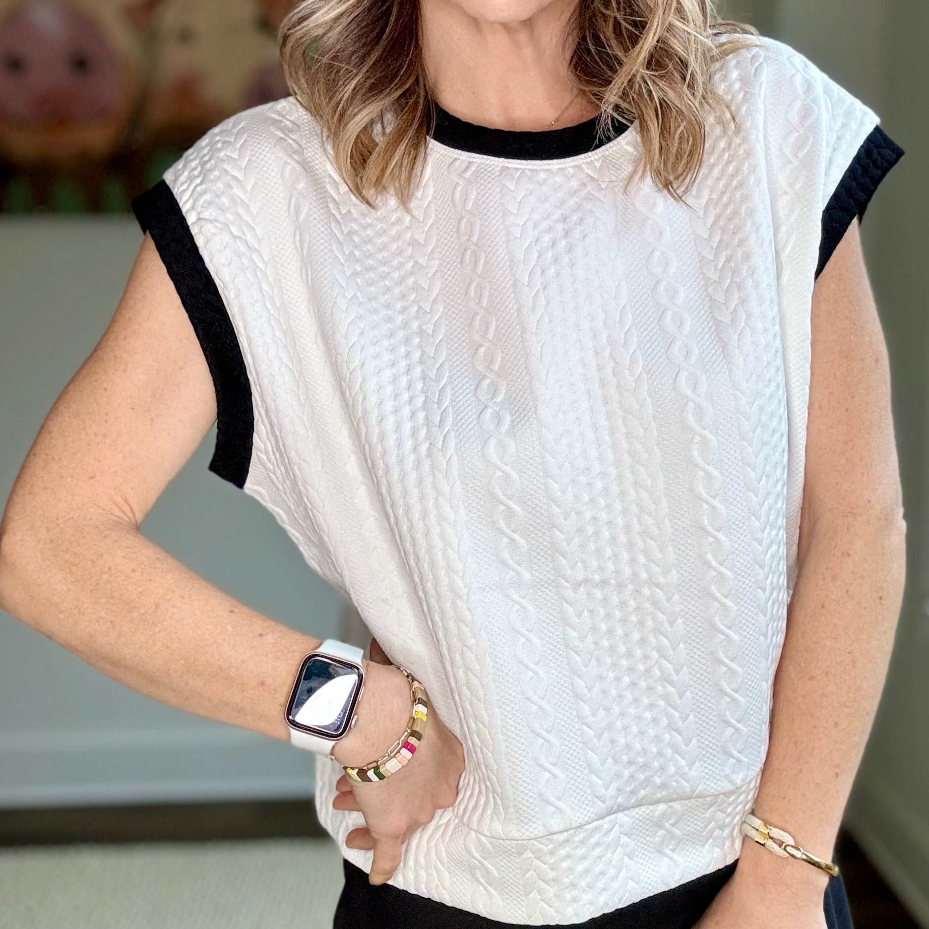 White cable knit textured cap sleeve top with black tipping at neck and armholes