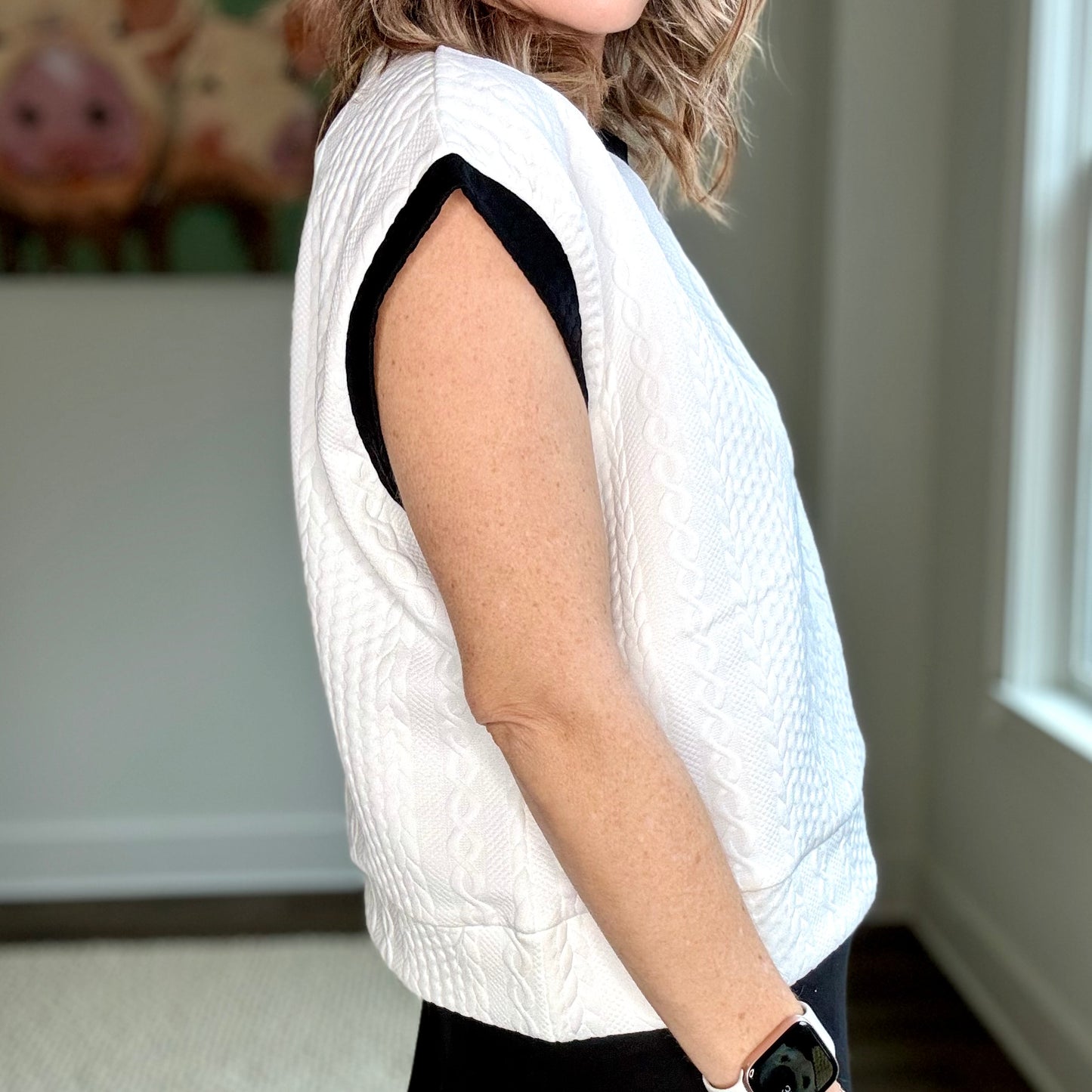 White cable knit textured cap sleeve top with black tipping at neck and armholes